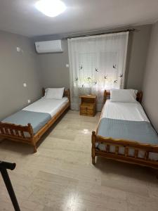 two twin beds in a room with a window at Plaza House in Kanáki