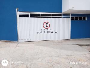 une porte de garage blanche avec un panneau sur celle-ci dans l'établissement Pousada avenida 03, à São Thomé das Letras