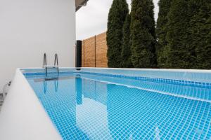 a swimming pool with a blue tile floor and trees at Aparthotel nah dran in Dingolfing