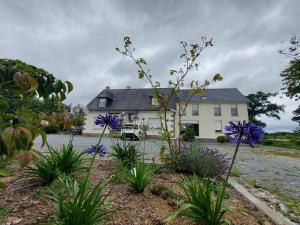 a white house with purple flowers in front of it at Maison de Luciné in Combourg