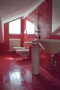 Baño rojo con lavabo y aseo en Casa Macina, en CastellʼAlfero
