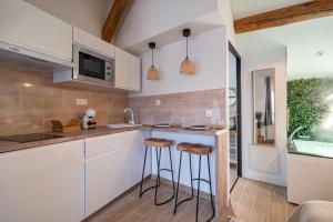 a kitchen with white cabinets and bar stools at BALI ROOM / Magnifique studio évasion JACCUZI in Montgeron