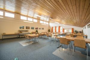 a large room with tables and chairs and windows at Jugendherberge Romanshorn in Romanshorn