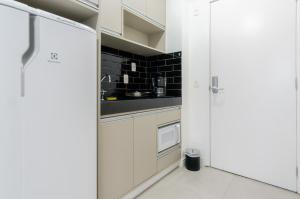 a kitchen with white cabinets and a white refrigerator at 360 Perdizes in São Paulo