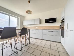 eine Küche mit weißen Schränken sowie einem Tisch und Stühlen in der Unterkunft Minven in Concarneau