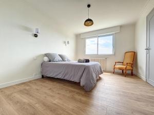 ein Schlafzimmer mit einem Bett, einem Stuhl und einem Fenster in der Unterkunft Minven in Concarneau