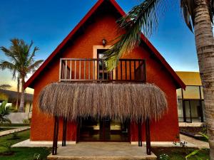 a red building with a balcony and a palm tree at LE VAHINÉ Eco-RESORT in Toliara