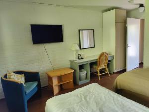 Cette chambre comprend un lit, un bureau et une télévision. dans l'établissement Jokirannan Majoitus, à Kokemäki