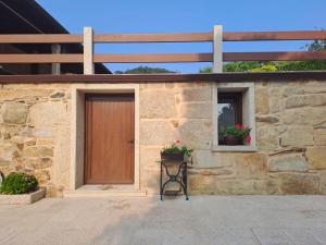 a stone building with a wooden door and two windows at O Peteiro in Redondela