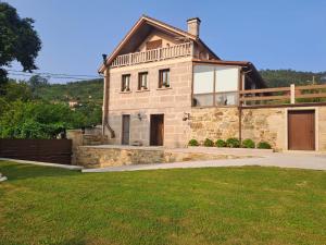 a large stone house with a grass yard at O Peteiro in Redondela