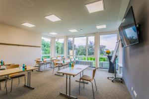 ケーニヒスヴィンターにあるJUFA Hotel Königswinter/Bonnのテーブルと椅子、薄型テレビが備わる教室です。