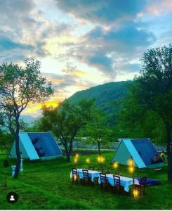 een groep tafels en tenten in een veld bij UNDER STARS HOUSE in Vermosh