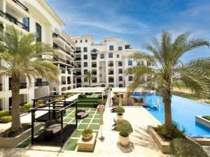an apartment complex with a swimming pool and palm trees at Luxury Golf View For Family 203A3 in Abu Dhabi