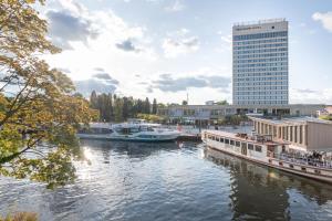 un groupe de bateaux amarrés dans une rivière avec un grand bâtiment dans l'établissement Mercure Hotel Potsdam City, à Potsdam