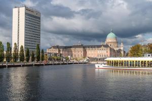 una barca su un fiume di fronte a un edificio di Mercure Hotel Potsdam City a Potsdam