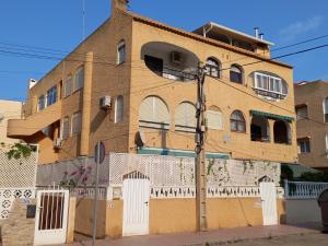 un edificio de ladrillo marrón con una valla blanca en Duplex apartment with a large sunny terrace 200 m from the sea en La Mata