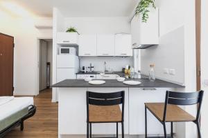 una cucina con armadi bianchi e un bancone con due sedie di [I Host Studio] - Broni 21 a Milano