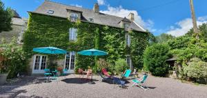 a house with chairs and umbrellas in front of it at LA VALLÉE DU LAUNAY GiTES in Taden