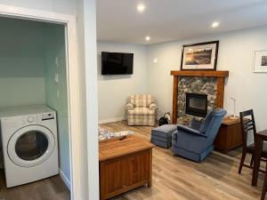 a laundry room with a washer and a living room with a fireplace at Kwalikum Kottage in Qualicum Beach