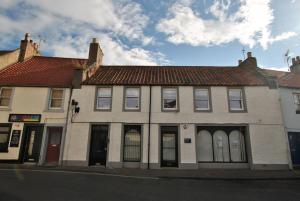 a white building with a red roof on a street at Murrays Neuk- stylish coastal apartment in Anstruther