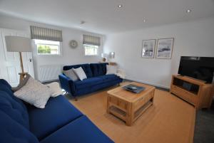 a living room with a blue couch and a tv at Murrays Neuk- stylish coastal apartment in Anstruther