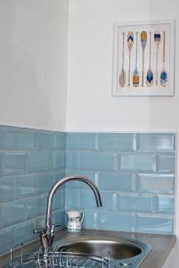 a kitchen with a sink and a blue tiled wall at Murrays Neuk- stylish coastal apartment in Anstruther