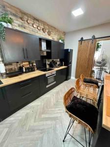 a kitchen with black cabinets and a table and chairs at Large Peak District National Park Holiday House in Hadfield