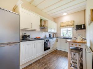 uma cozinha com armários brancos e um frigorífico em Paddock Cottage - Thorpe Arnold Melton Mowbray em Melton Mowbray