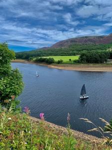 a boat with a sail on a river with hills at Large Peak District National Park Holiday House in Hadfield