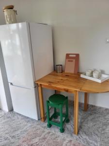 a wooden table with a green stool next to a refrigerator at Domek letniskowy Dolice in Dolice +6 photos