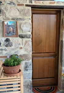 une porte en bois dans un mur en pierre avec une plante en pot dans l'établissement Cantina nel Castello, à Montegiovi