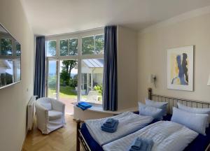 a bedroom with a bed and a chair and a window at Meerblick - Villa Achterkerke in Heringsdorf