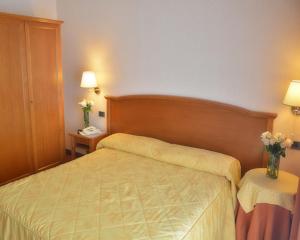 een slaapkamer met een bed en 2 tafels met bloemen bij Villa Sirena Hotel e Ricevimenti in Durazzano