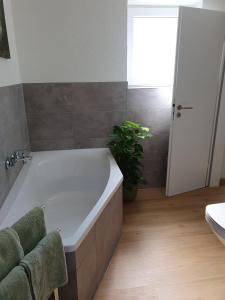 La salle de bains est pourvue d'une baignoire et d'une plante. dans l'établissement Gästehaus Spatzennest Wohnung 2, 