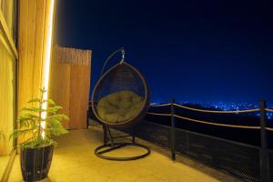a swing chair sitting on a balcony at night at Terhabb Cottages in Abha