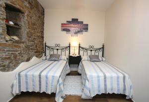 a bedroom with two beds and a brick wall at Apartamentos Rurales San Xillao in Ribadeo