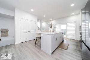 eine weiße Küche mit weißen Schränken und einem Tisch in der Unterkunft Urban Utopia - Hot Tub - King Bed - BBQ - Sleeps 16 - Garage in Edmonton + 74 Fotos