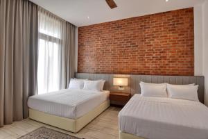 a bedroom with two beds and a brick wall at Elshape Holiday VILLA in Masjid Tanah