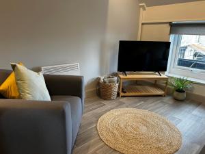a living room with a couch and a flat screen tv at The Salt Locker in Porthleven