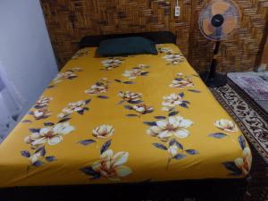 a bed with a yellow blanket with flowers on it at Magpie homestay in Bukit Lawang
