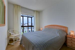 um quarto com uma cama, uma cadeira e uma janela em Duquesa Port retreat em Manilva