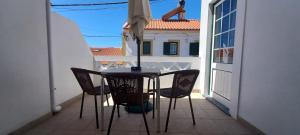 stół i krzesła na balkonie z widokiem na budynek w obiekcie Apartamentos Naturalis w mieście Vila Nova de Milfontes