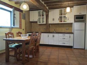 cocina con armarios blancos, mesa y sillas en Casa Rural Espeñitas en La Alberca