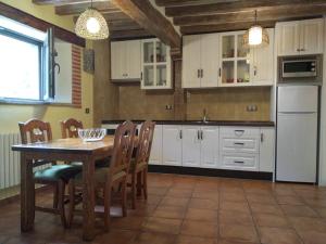 a kitchen with white cabinets and a table and chairs at Casa Rural Espeñitas in La Alberca