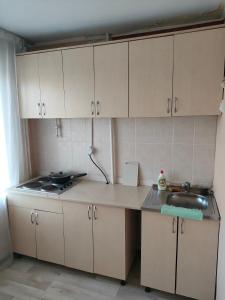 a kitchen with white cabinets and a sink at Galeto 22 Apartments in Semey