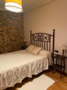 a bedroom with a bed and a stone wall at Casa Benaxo in Currelos