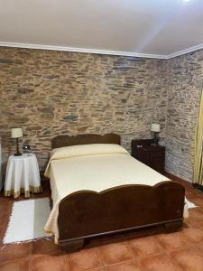 1 dormitorio con 1 cama grande y pared de piedra en Casa Benaxo, en Currelos