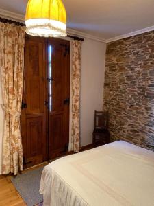 een slaapkamer met een bed en een stenen muur bij Casa Benaxo in Currelos