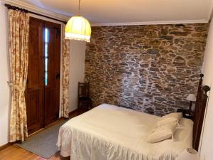 a bedroom with a bed and a brick wall at Casa Benaxo in Currelos