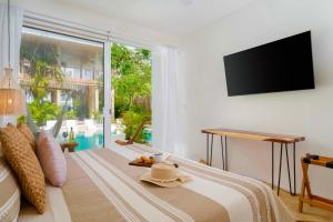 Schlafzimmer mit einem Bett und einem Flachbild-TV in der Unterkunft Beautiful Swim-Up Apartment with Private Terrace & Hammoc, Pool & Gym in Tulum